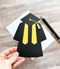 a hand holding a piece of paper with a graduation cap and tassel on it