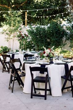 an outdoor table set up with black chairs and white linens for a formal dinner