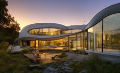 an unusual house with curved walls and glass windows on the outside is lit up at sunset