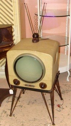 an old fashioned tv sitting on top of a stand