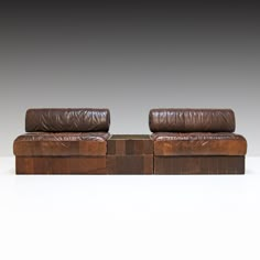 two brown leather couches sitting next to each other on top of a white floor