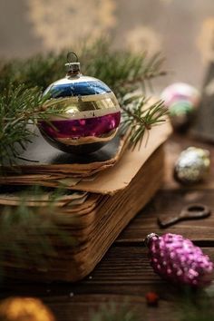 an ornament sitting on top of a book next to christmas ornaments and pine branches