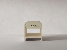 a small white table sitting on top of a white floor next to a gray wall