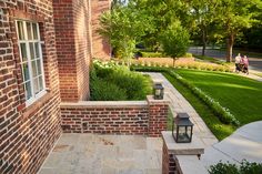 a brick building with two lanterns on the outside and grass in the front yard behind it