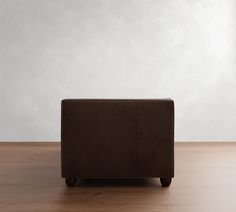 a brown couch sitting on top of a hard wood floor next to a white wall