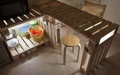 a table made out of wooden pallets with a basket on it and two stools next to it