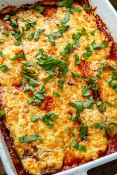 a casserole dish with cheese, sauce and fresh herbs on the top is ready to be eaten