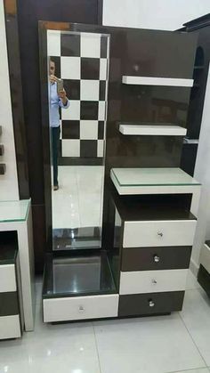 a person taking a photo in a mirror next to some dressers and tables with checkered walls