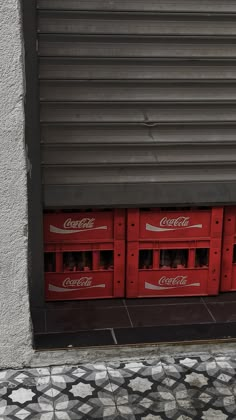 coca - cola crates are lined up on the side of a building in front of a door