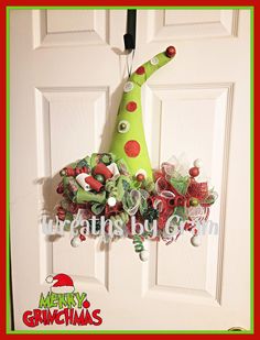 a green christmas hat hanging from the front door decorated with candy canes and candies