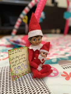 two elfs sitting on top of a table next to a sign