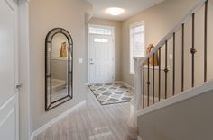 an entry way with a mirror, door and stairs leading up to the second floor