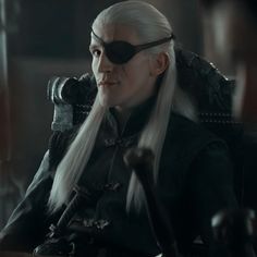 the white haired man is sitting in a chair with long hair and glasses on his face