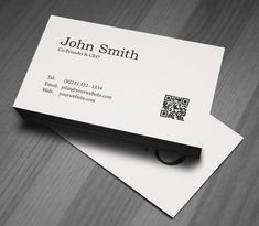 two business cards with qr code on them sitting on top of a wooden table