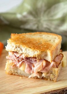 a ham and cheese sandwich sitting on top of a wooden cutting board