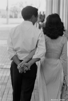 a man and woman holding hands walking down the street