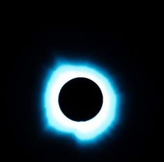 a black hole in the dark with blue light coming out from it's center