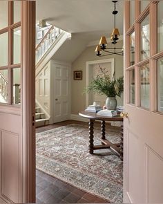 an entry way with a rug, table and stairs leading to the second floor area