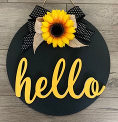 a black and yellow door hanger with a sunflower on it that says hello