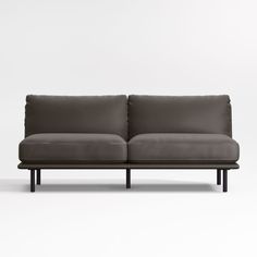 a gray couch sitting on top of a white floor next to a black metal frame