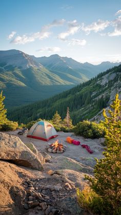 a tent set up on top of a mountain with trees and mountains in the background