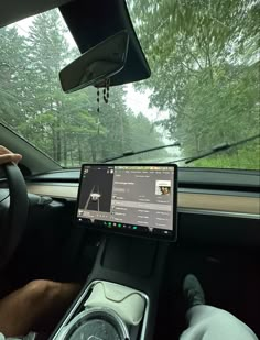 a car dashboard with an electronic device in the passenger's seat and trees in the background