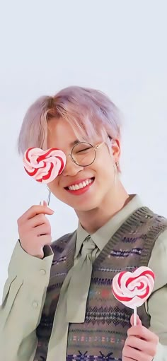 a person holding two lollipops in their hands and smiling at the camera