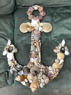 an anchor made out of shells and seashells on a green couch with a pillow