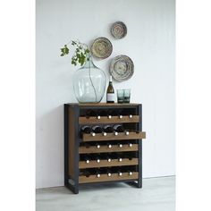 a wine rack with several bottles on it next to a vase and plate wall hangings