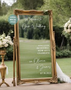 a large mirror sitting on top of a wooden stand next to flowers and greenery