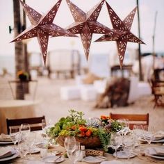 three stars hanging over a dining table with place settings and flowers on the table top