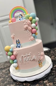 a three tiered cake decorated with cartoon characters and rainbows on the top layer