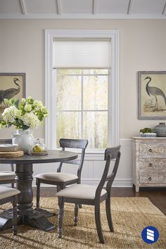 a dining room table with two chairs and a vase filled with flowers on top of it