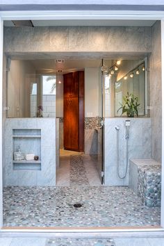 a bathroom with two sinks and a shower in the middle, surrounded by marble tiles