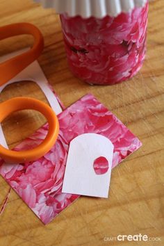 some pink flowers are sitting on a table next to scissors and a cupcake liner