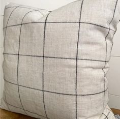 a white and black checkered pillow sitting on top of a wooden floor next to a wall