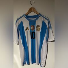 a soccer jersey hanging on a hanger next to a white and blue striped wall