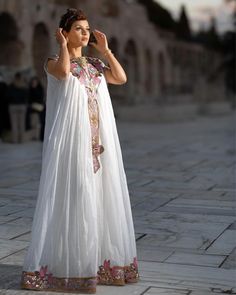 a woman in a white dress is talking on her cell phone