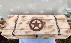 a wooden box with a metal star on it and chains hanging from the top, along with a white towel