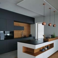 a modern kitchen with black counter tops and wooden accents on the cabinets, along with hanging lights