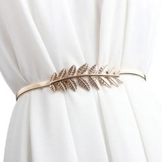 a close up of a white dress with a gold leaf belt on it's waist