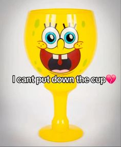 a yellow wine glass with an emoticive expression on the side and words that read i can't put down the cup