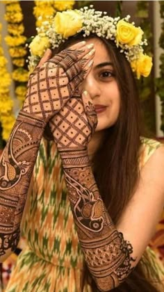 a woman with henna on her hands and yellow flowers in the hair is smiling at the camera