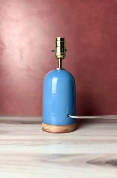 a blue bottle sitting on top of a wooden table next to a white object with a metal hook in it