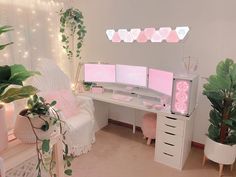 a white desk topped with two computer monitors next to potted plants and greenery