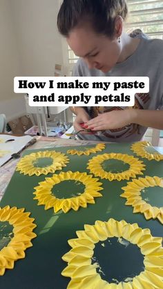 a woman is making sunflowers out of paper and applying them with glue on the table