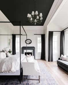 a white bed sitting in a bedroom next to a black and white couch on top of a hard wood floor