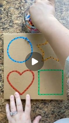 someone is making a heart shape out of construction paper