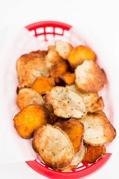 some fried potatoes in a red basket on a white table