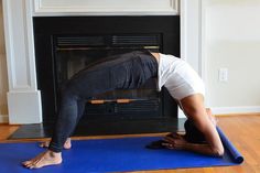 a woman is doing yoga in front of a fireplace